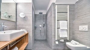 A modern bathroom with a large sink, mirror, shower, and toilet.