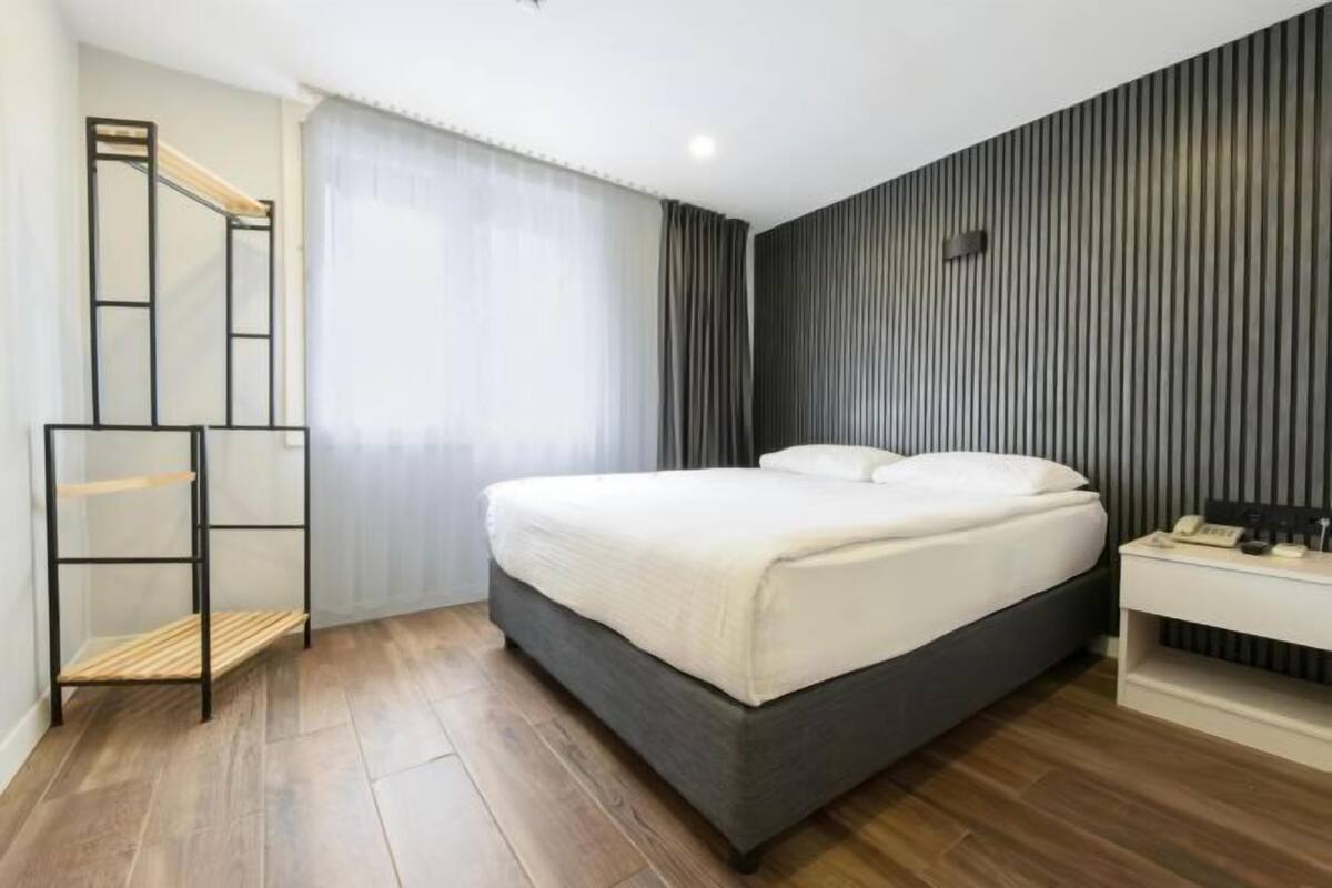 A modern bedroom with a bed, bedside table, and a mirror.