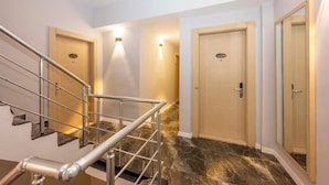 A modern hotel lobby with a marble staircase, a reception desk, and a glass-enclosed elevator. - Legend Tulip Hotel (Antalya)