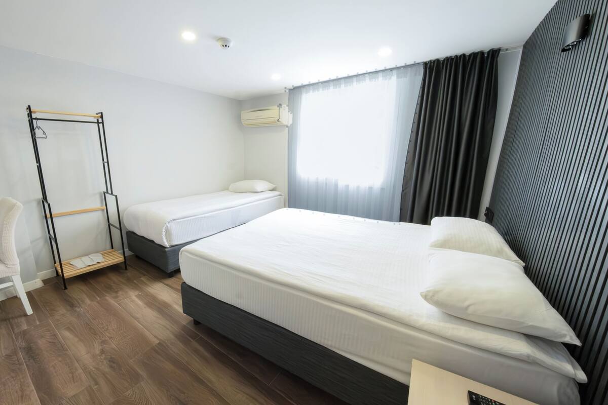 A hotel room with a bed, a desk, a chair, a wardrobe, and a window with curtains.