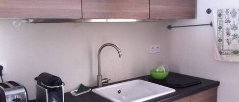 A kitchen with wooden cabinets, a black countertop, a white sink, a toaster, and a green bowl.