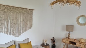A bedroom with a bed, a desk, a chair, a hanging light fixture, a macrame wall hanging, and a mirror. - Charming 1-bed House (Silves)