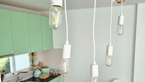 A modern kitchen with green cabinets, a wooden beam ceiling, and pendant lights with exposed bulbs. - Charming 1-bed House (Silves)