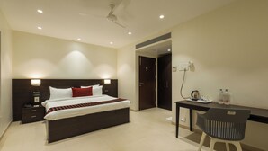 A modern hotel room with a large bed, bedside tables, a desk with a chair, and a ceiling fan.