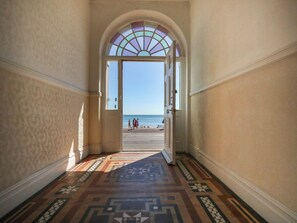 A hallway with a patterned floor leading to a door with a stained glass window. - 123 On The Sea - Captain's View (Weymouth)