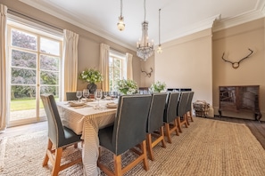 A dining room with a large table set for six, surrounded by chairs with dark upholstery and wooden frames. - The Vicarage and Cottage -  two beautiful properties in Great Limber, sleeping 16 guests (Great Limber)