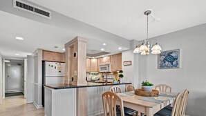 Una cocina moderna con una isla central, armarios de madera y un comedor con mesa y sillas.