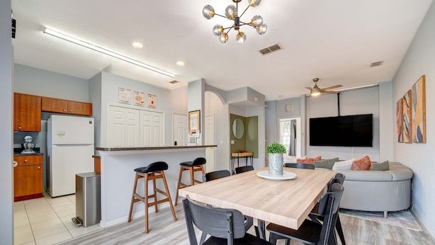 A modern kitchen with wooden cabinets, a white refrigerator, and a stainless steel sink. - 4BR family retreat near Disney w/ patio (Kissimmee)