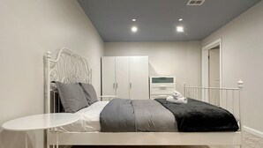 Une chambre à coucher avec un lit, une petite table, une armoire et un miroir.