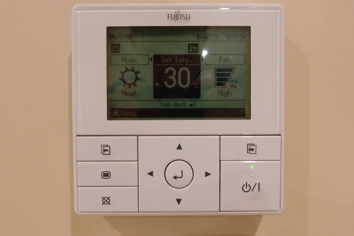 A Fujitsu air conditioning unit with a digital display, control buttons, and a power indicator.