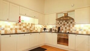 A modern kitchen with white cabinets, a stainless steel range hood, and a checkered backsplash. - Pen-y-les (Wadebridge)