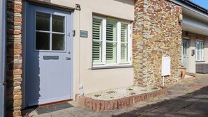 A building with a stone facade, a white door, and a window with shutters. - Pen-y-les (Wadebridge)