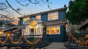 Ett tvåvåningshus med en veranda, en liten trädgård framför huset med ljusslingor och en brevlåda.