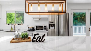 A modern kitchen with a central island, stainless steel appliances, and a hanging light fixture. - Bothell Family Friendly Modern Home, 2 AC, I405 (Bothell)