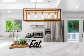 A modern kitchen with a central island, stainless steel appliances, and a hanging light fixture.