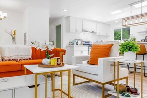 A modern living room with a sofa, coffee table, and a dining area with a table and chairs.