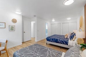 A modern bedroom with a bed, bedside table, lamp, and a chair.