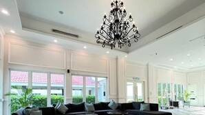 Um hall amplo com piso xadrez em preto e branco, um sofá preto e um lustre.