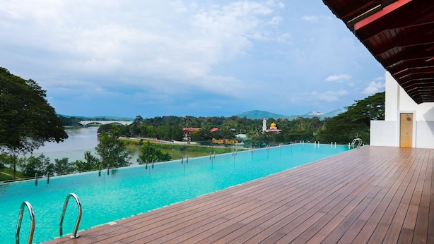 Um deck de madeira com piscina, com vista para um rio e vegetação.