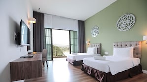 Quarto de hotel com duas camas, uma secretária, uma televisão e varanda com cortinas.