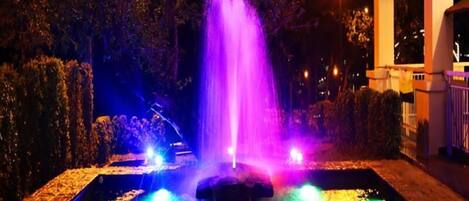 Una fontana illuminata da luci colorate di notte.