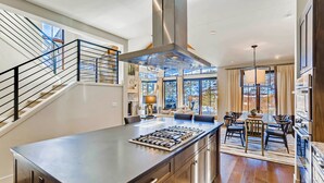 Une cuisine moderne dotée d’un îlot central, d’appareils électroménagers en acier inoxydable et d’un escalier avec une rampe.