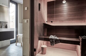A modern bathroom with a wooden vanity, a bench, and a small table with a towel and a cup. - Villa Baltique Sellin (Sellin)