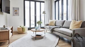A modern living room with a sofa, a coffee table, a TV, and large windows. - Villa Baltique Sellin (Sellin)