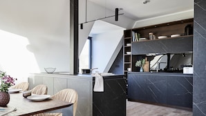 A modern kitchen with a central island, built-in shelves, and a dining area with chairs and a table. - Villa Baltique Sellin (Sellin)