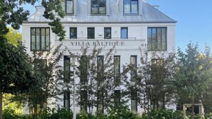 A white building with the name "Villa Baltiqué" on the facade, featuring multiple windows and a sloped roof with skylights. - Villa Baltique Sellin (Sellin)