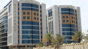 Twee hoogbouwgebouwen met de namen 'Saray Residence' en 'Hotel Al Arabi' op de gevels.