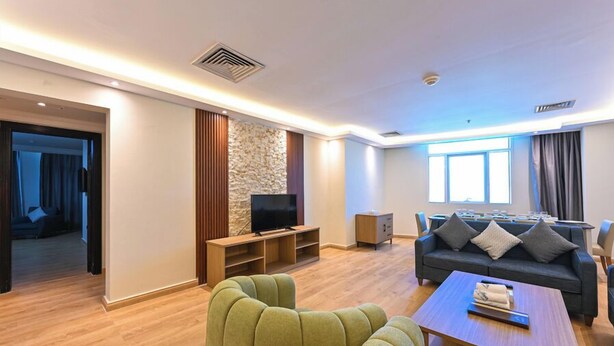 Een moderne woonkamer met een bank, een televisie en een eethoek.