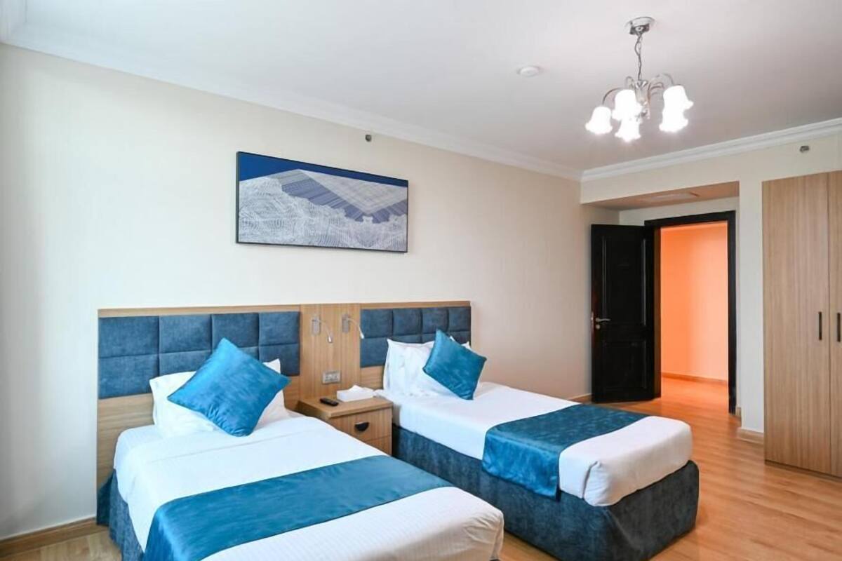 Ett hotellrum med två sängar, en sänggavel i trä, ett nattduksbord, en tavla på väggen och en garderob.