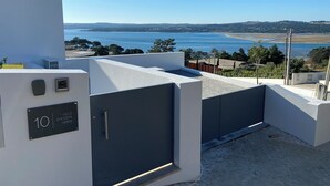 A modern building with a flat roof, a view of a beach, and a sign indicating the address.