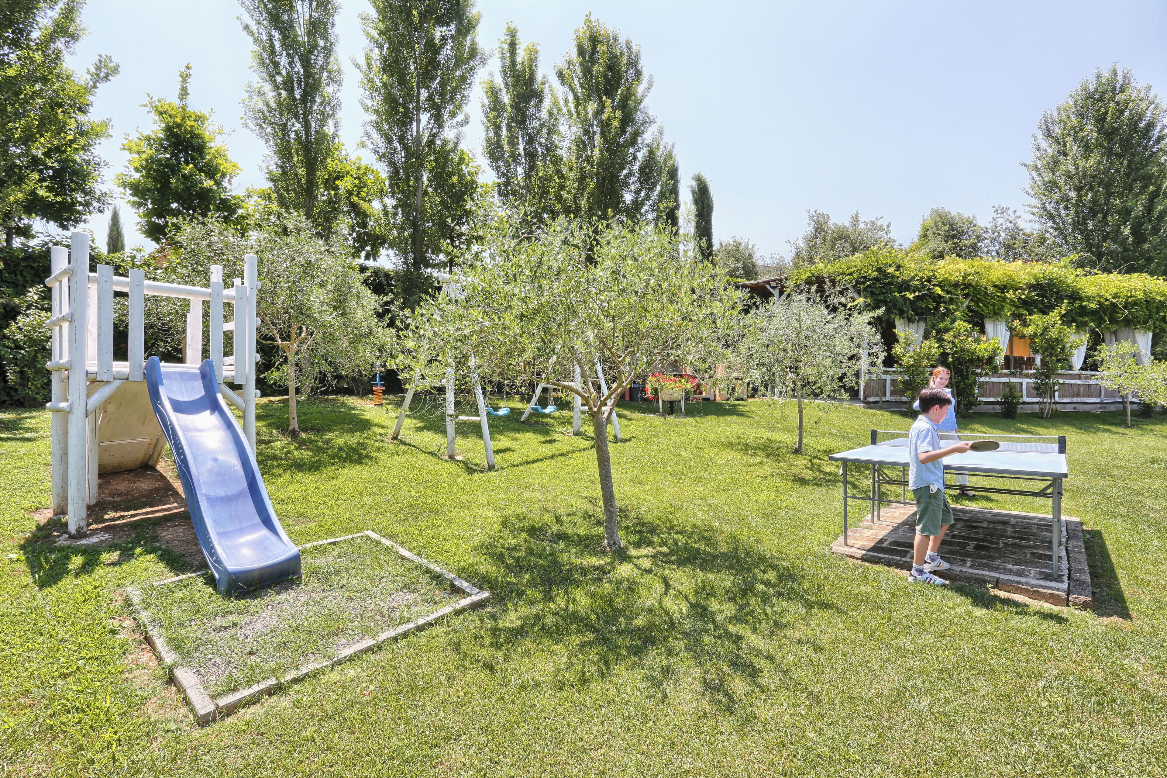 A playground with a slide and a table tennis table.
