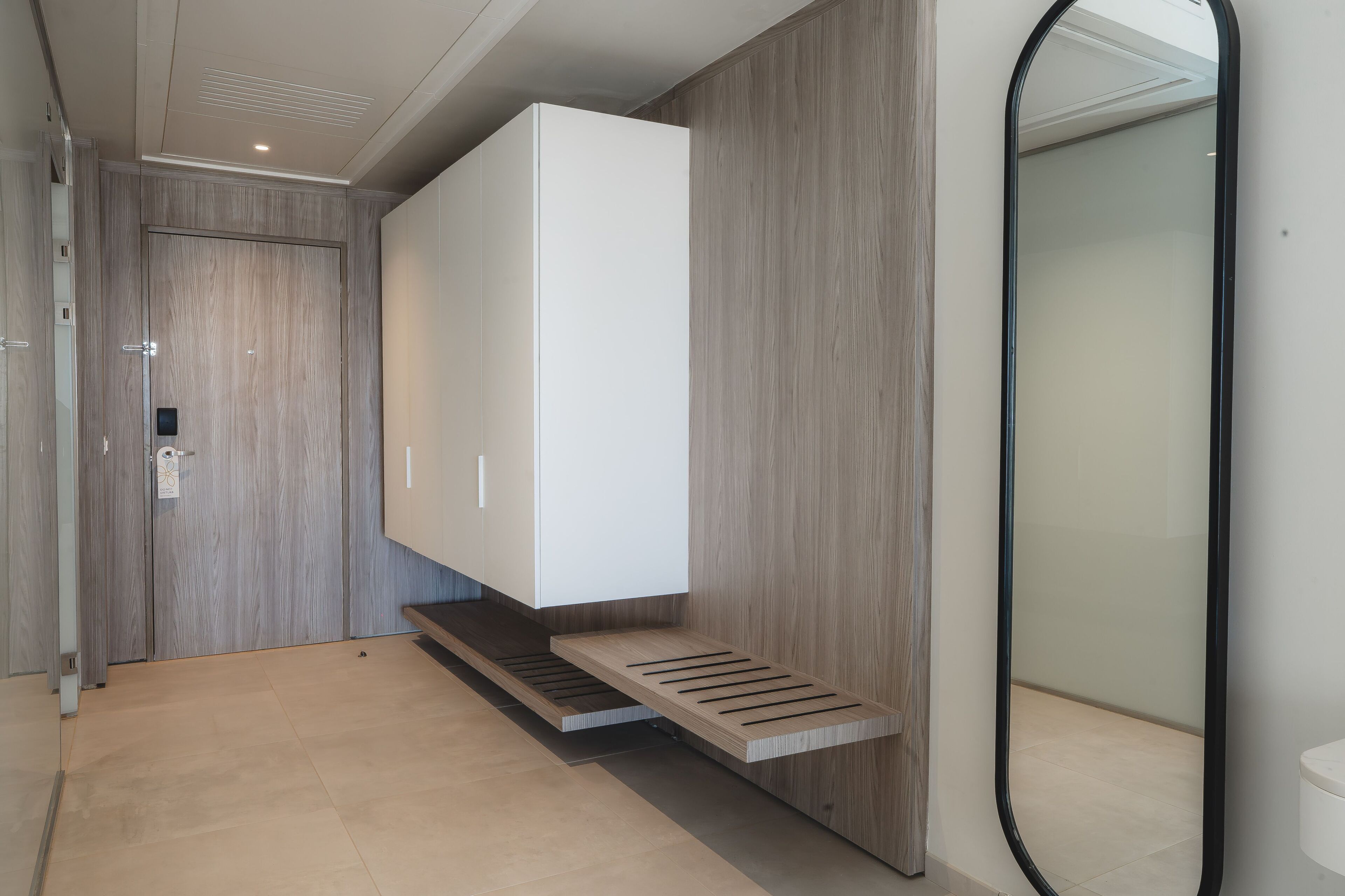 Ein modernes Badezimmer mit einem großen Spiegel, einem weißen Schrank und einem Holzlager.