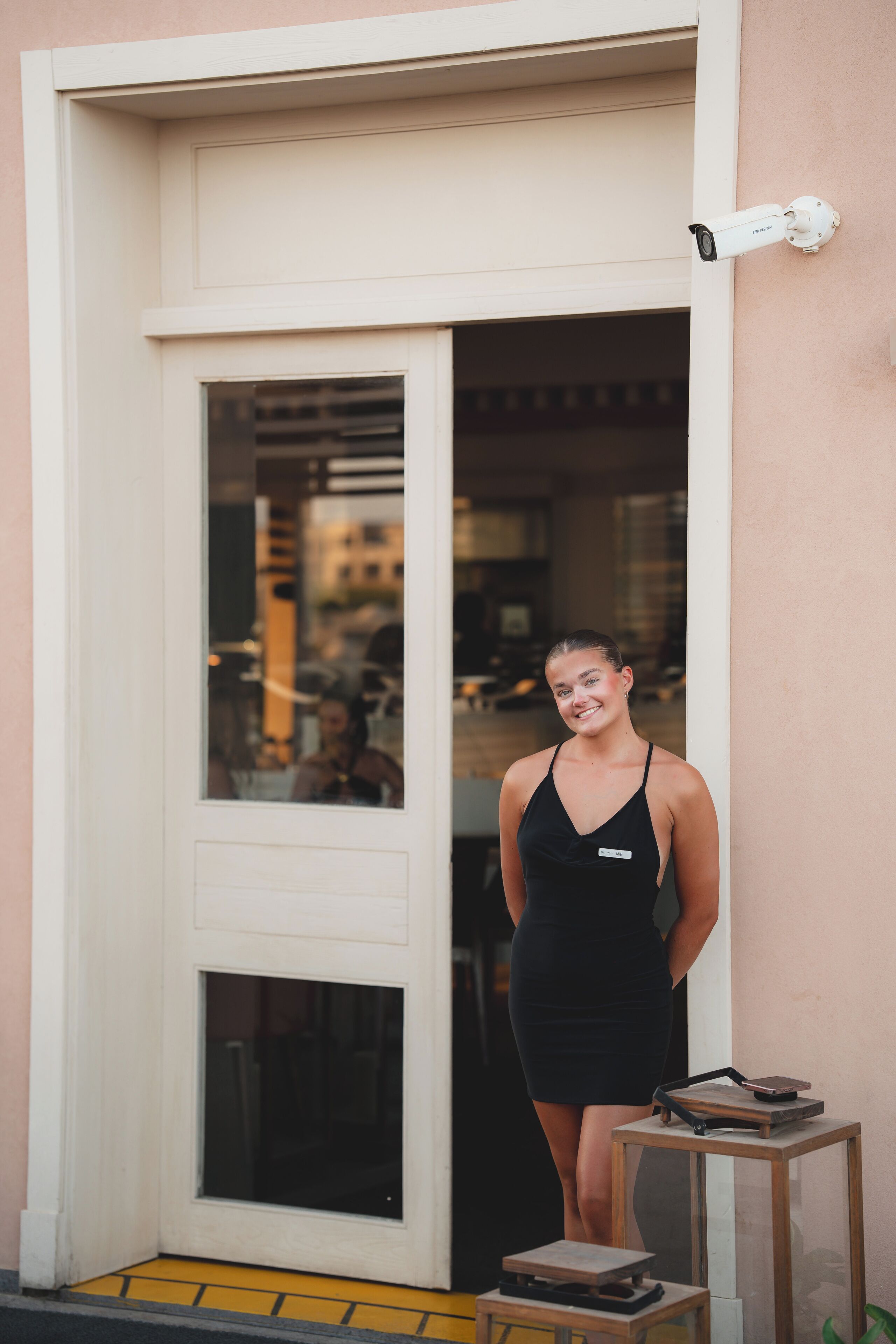 A person standing at a door with a security camera above it.