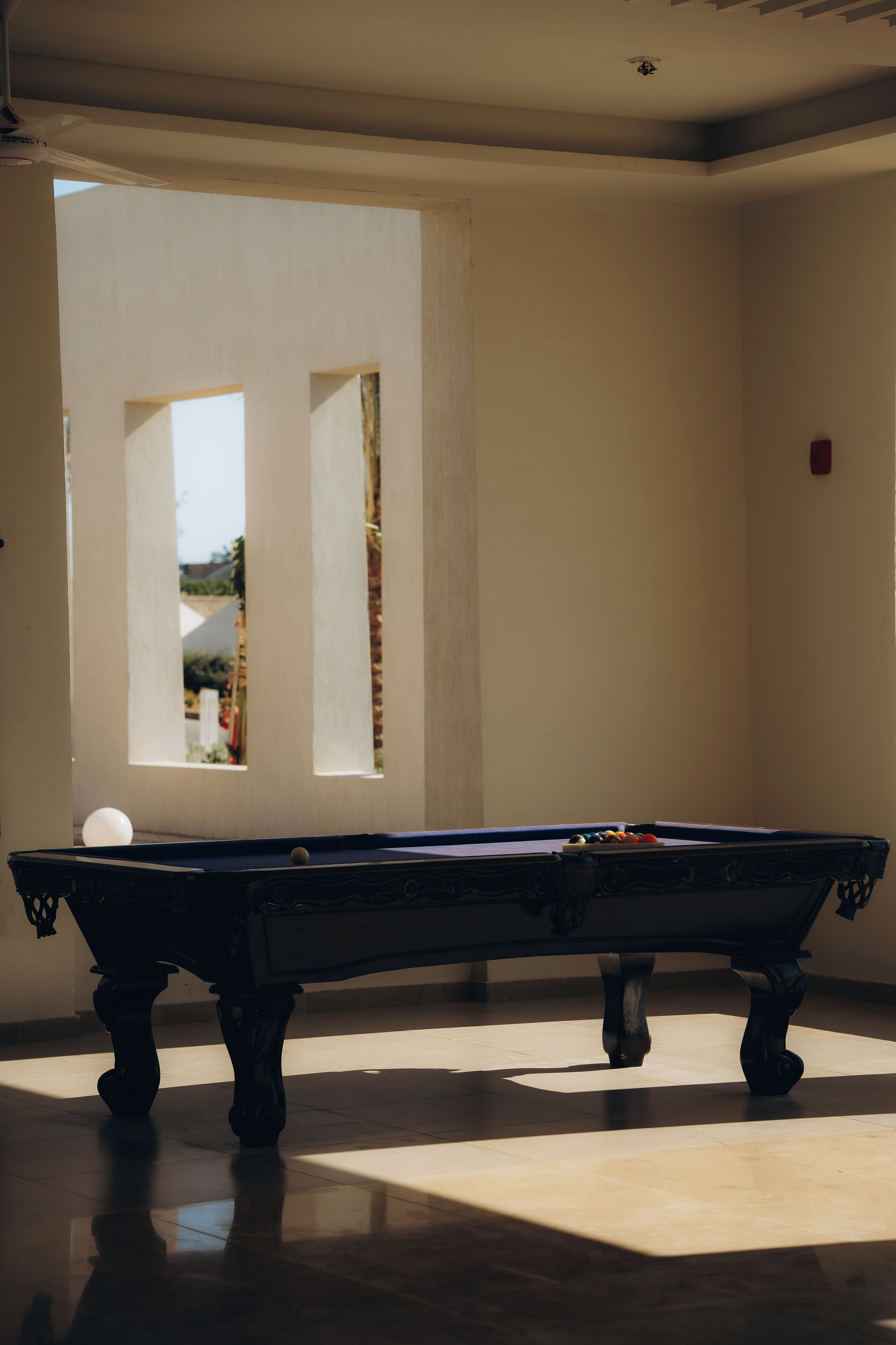 Una mesa de billar en una habitación con vistas a través de una ventana.