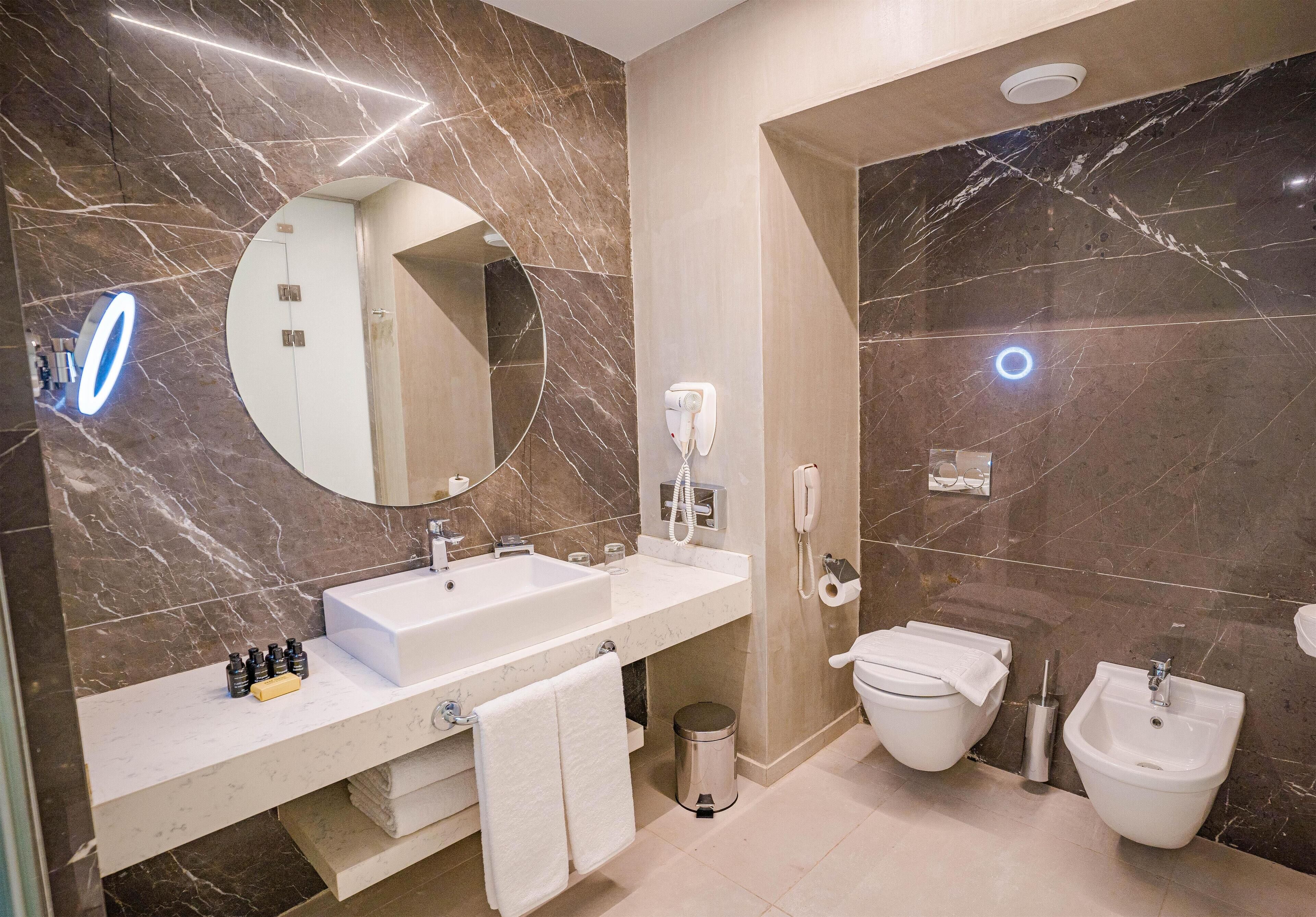 Une salle de bain moderne avec un grand lavabo, un miroir et deux toilettes.