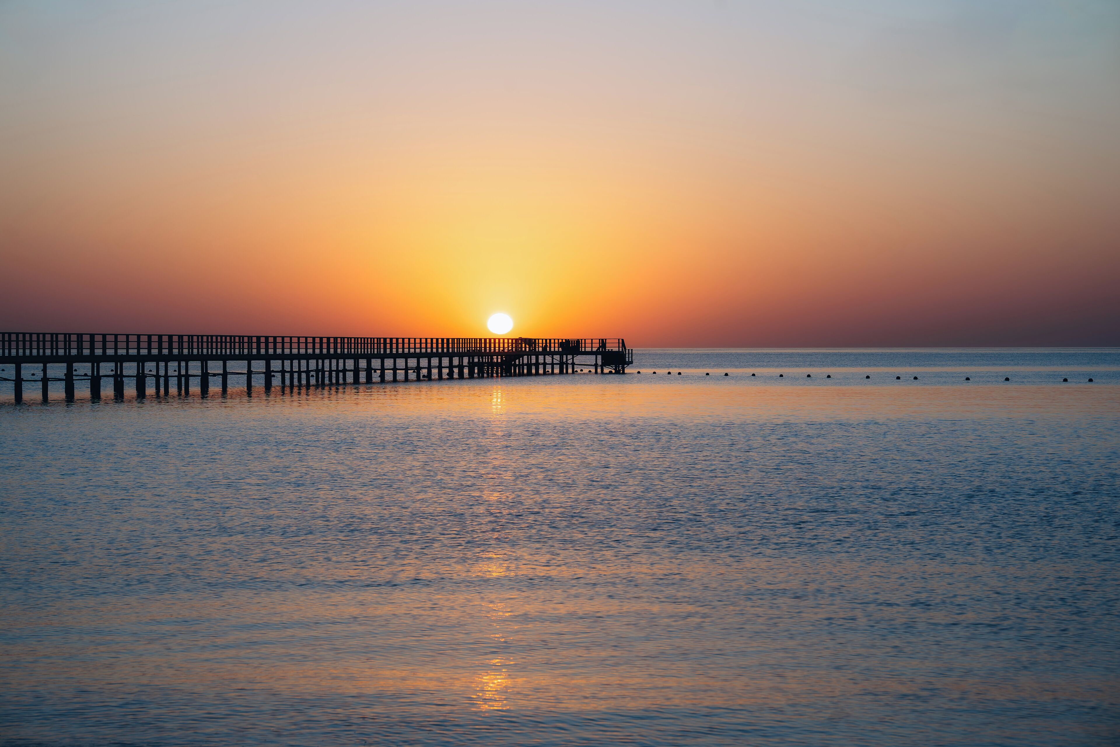 A pier extending into calm waters at sunset.