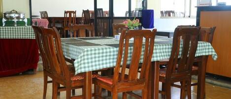 A dining area with wooden chairs and tables covered with checkered tablecloths.