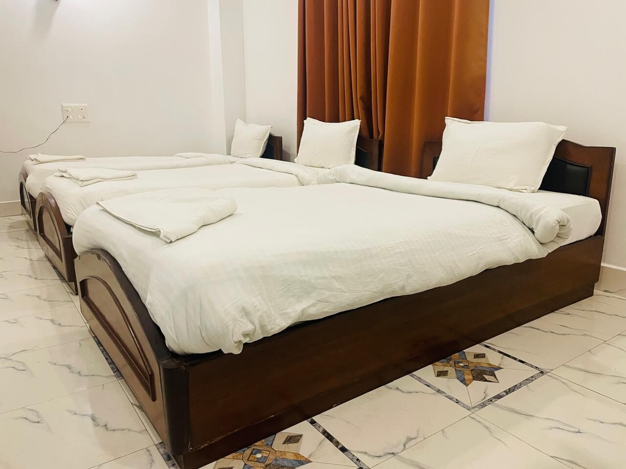 A hotel room with a large bed, a smaller bed, and a bathroom.
