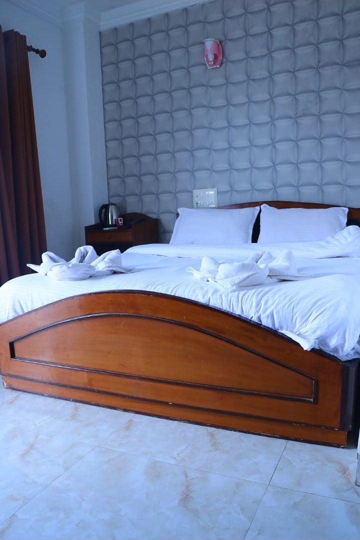 A neatly made bed with white linens, a wooden headboard, and a grey tufted headboard panel.