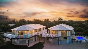 Dos villas frente al agua con balcones, piscina y vistas del paisaje circundante.