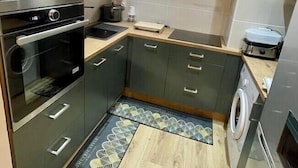 Une cuisine compacte dotée d’appareils électroménagers intégrés, d’un lave-linge et d’un four à micro-ondes.