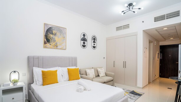 A modern hotel room with a large bed, a sofa, a desk, and a wardrobe. - Tanin - Sleek Studio Offering Unobstructed City Views (Dubai)
