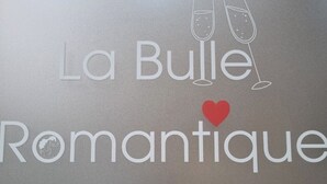Kyltti, jossa lukee ”La Bulle Romantique”, ja kaksi samppanjalasia, joiden päällä on sydämen muotoinen koriste.