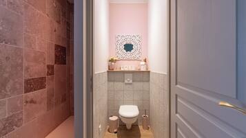 Ein Badezimmer mit Toilette, Waschbecken und einem dekorativen Spiegel.