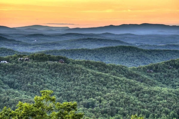 A mountainous landscape with dense forestation and scattered buildings.