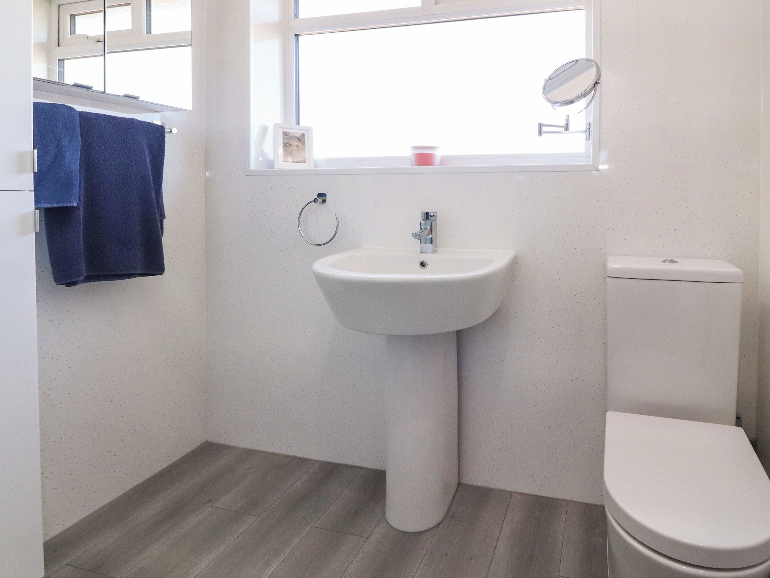 A bathroom with a white sink, a toilet, and a window above the sink.
